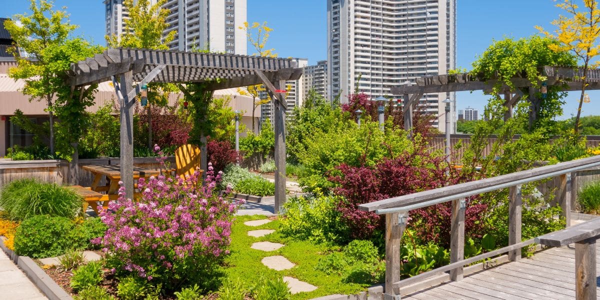 Rooftop garden with lush greenery, pergolas, and city skyscrapers in the background.